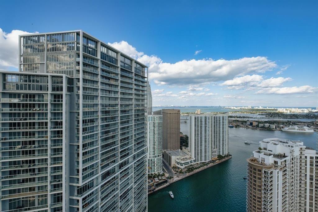 An elevated view shows a waterway with a boat passing between modern high-rise buildings — 465 Brickell Avenue # 2706, Miami FL 33131, MIAMI, FL