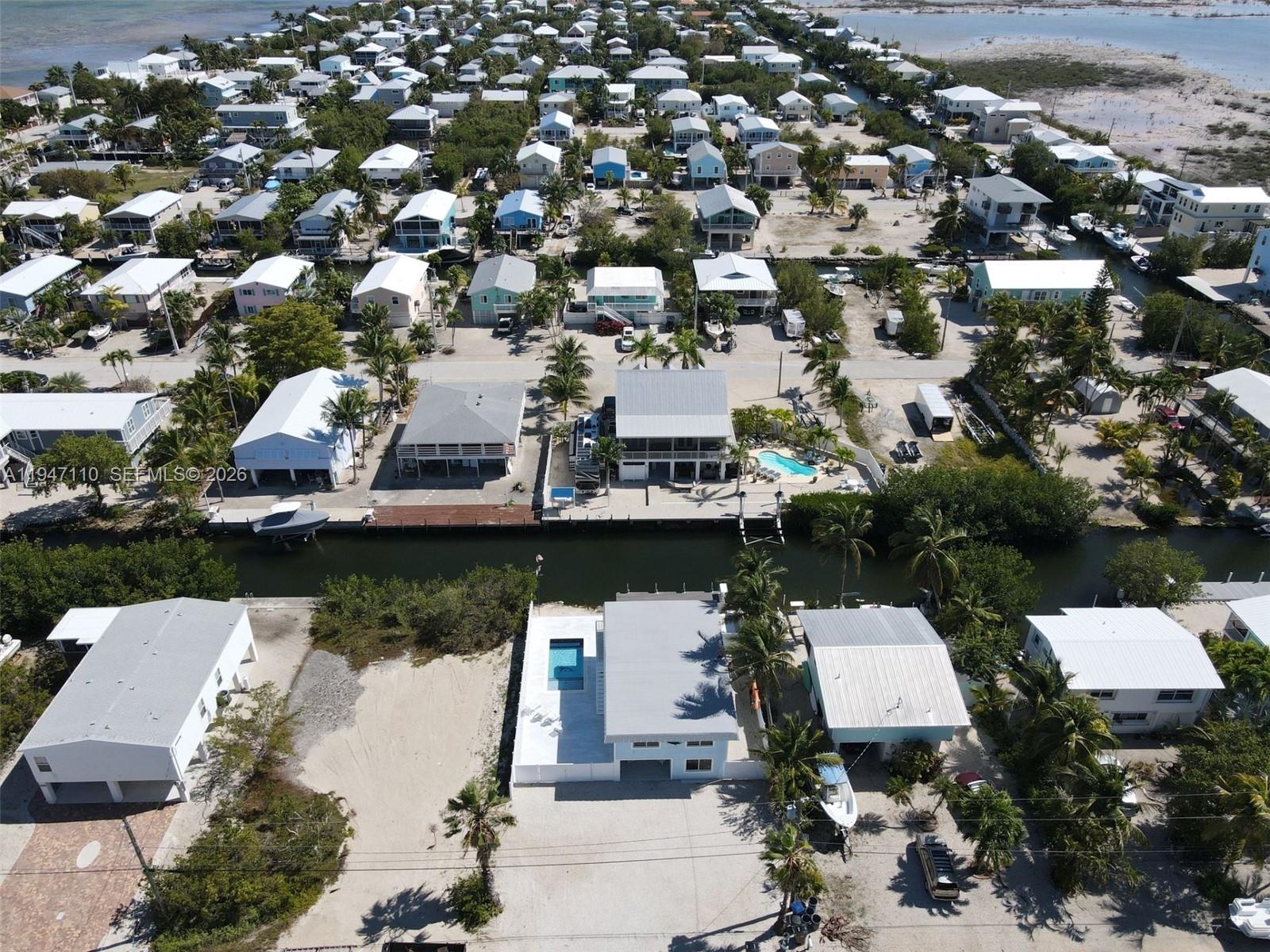 An aerial view shows a coastal neighborhood with houses, canals, and private swimming pools — 27346 Martinique Ln # 27346, Middle Keys FL 33042, MIDDLE KEYS, FL