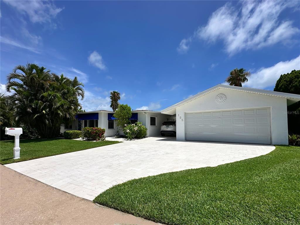 A stone monument sign for Isle of Palms stands beside a palm tree and street — 155 112TH AVENUE UNIT A, TREASURE ISLAND, FL