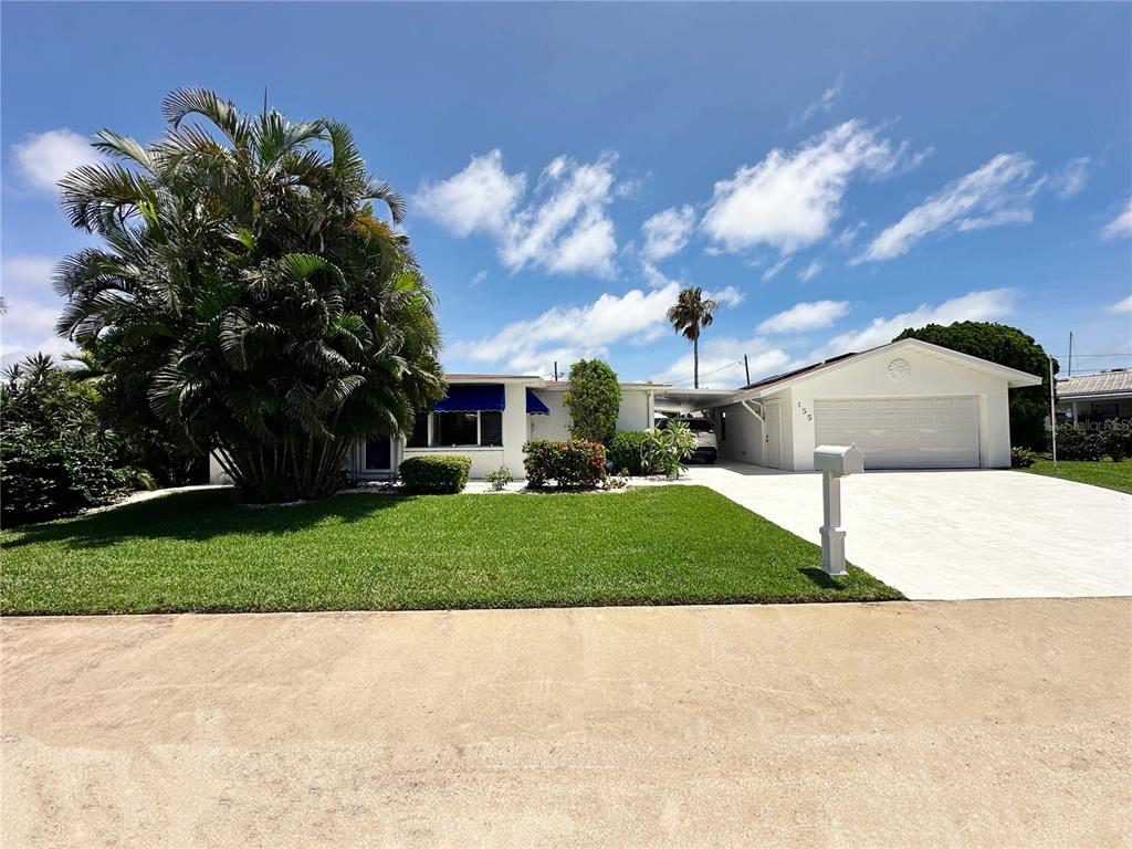 A white single-story house with a paved driveway, a two-car garage, and palm trees — 155 112TH AVENUE UNIT A, TREASURE ISLAND, FL
