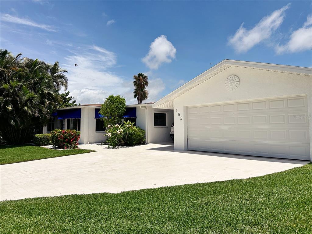 A white house exterior features a blue awning, a glass door, and a tiled porch — 155 112TH AVENUE UNIT A, TREASURE ISLAND, FL