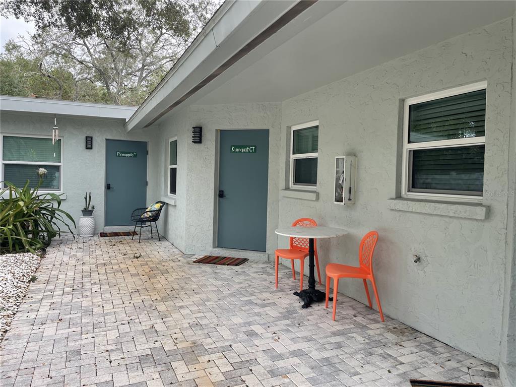 A paved patio features two blue doors labeled Pineapple and Kumquat CT with outdoor seating — 1912 MORRILL UNIT 1916, SARASOTA, FL