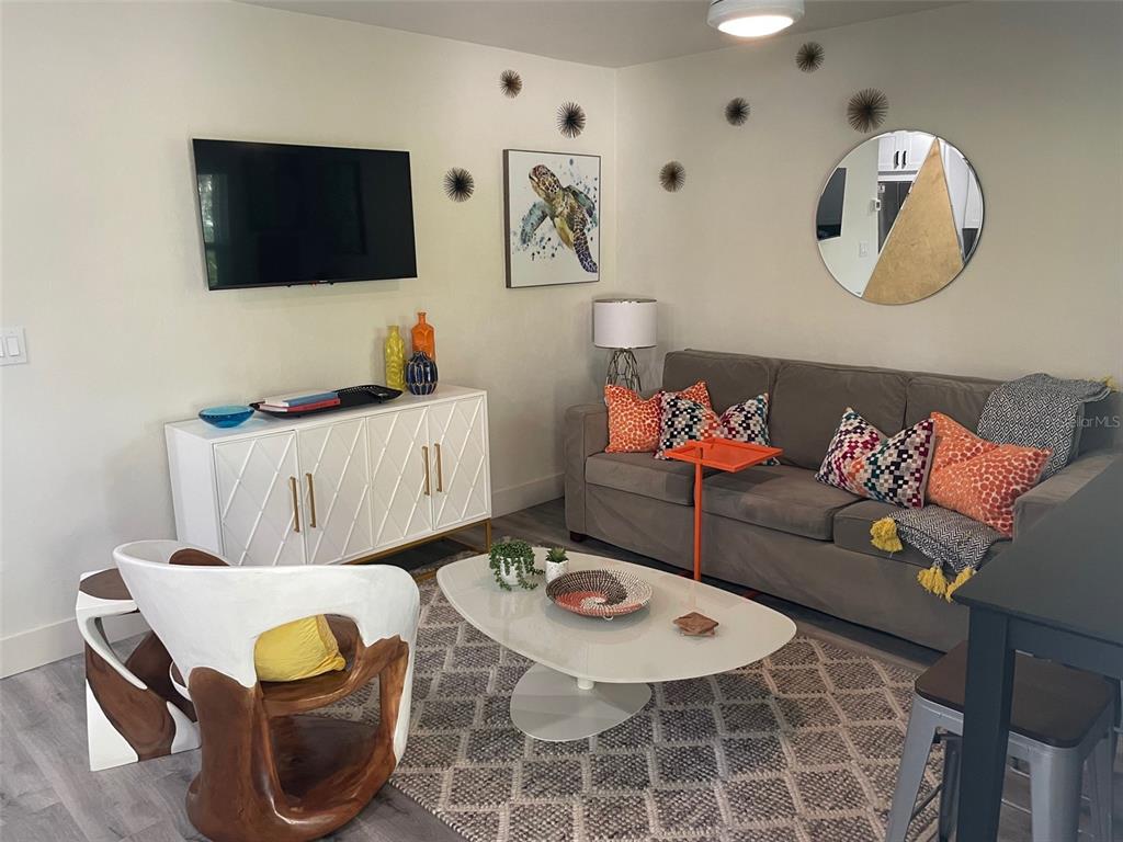 A living room features a grey sofa, white media console, and a modern coffee table — 1912 MORRILL UNIT 1916, SARASOTA, FL