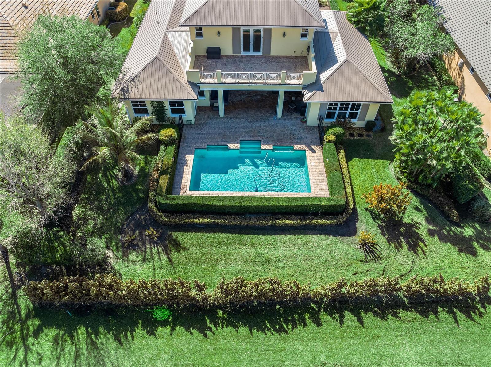 An aerial view shows a two-story house with a pool, patio, and manicured hedges — 7634 S Polo Grounds Lane, Vero Beach FL 32966, VERO BEACH, FL