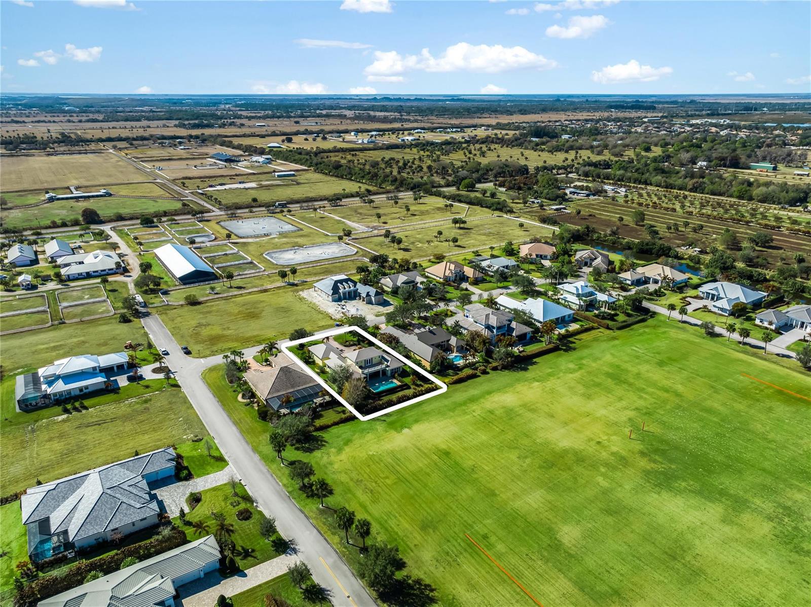 An aerial view shows a residential house with a pool, surrounded by fields and pastures — 7634 S Polo Grounds Lane, Vero Beach FL 32966, VERO BEACH, FL