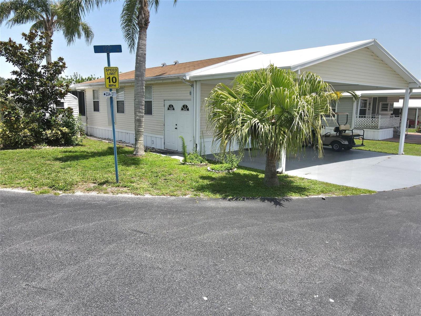 A single-story mobile home with a carport, palm tree, and a speed limit sign — 12310 SE 143rd Avenue, FL 34974, FL