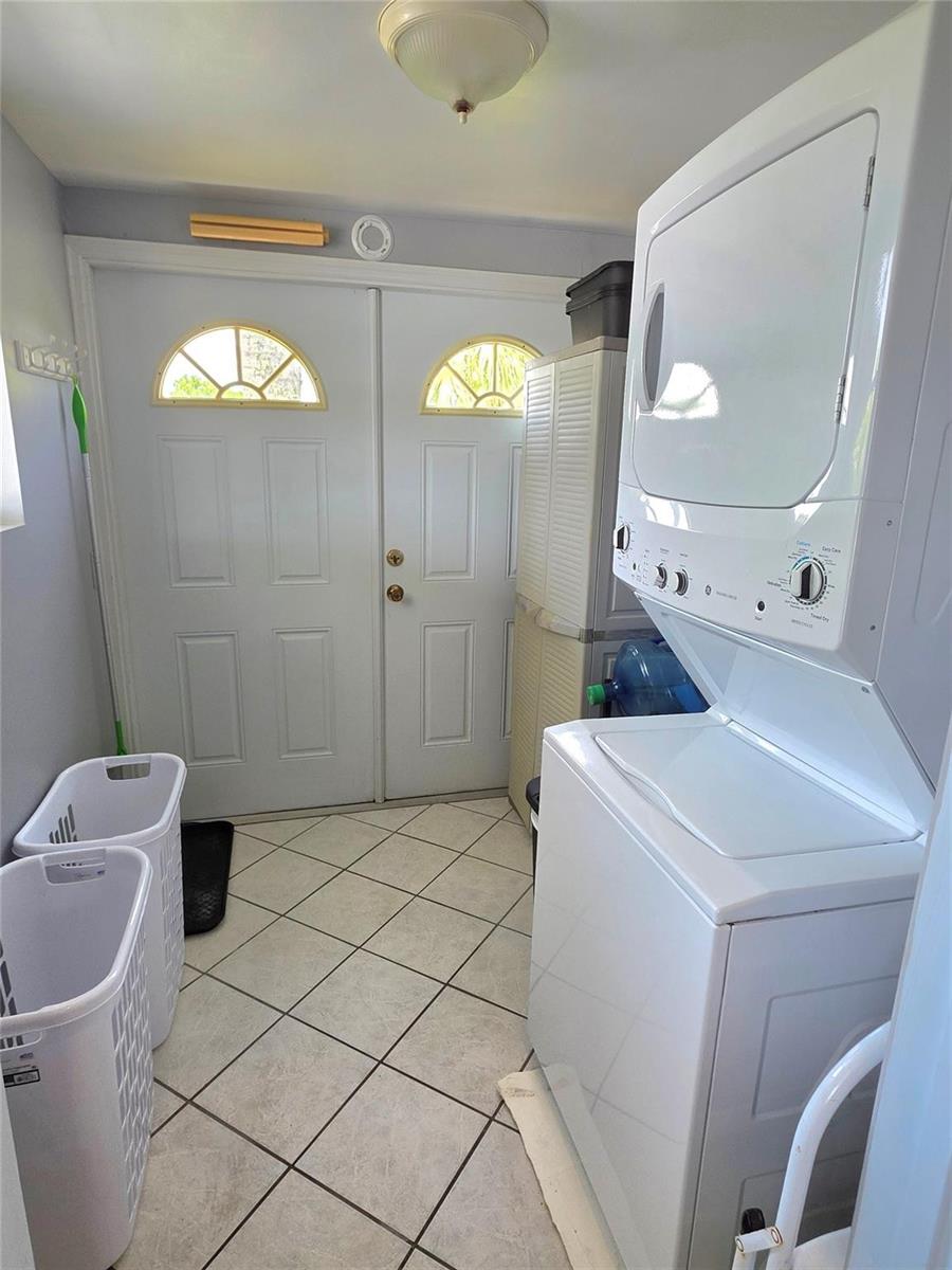 A laundry room features a stacked washer and dryer, tile flooring, and double entry doors — 12310 SE 143rd Avenue, FL 34974, FL