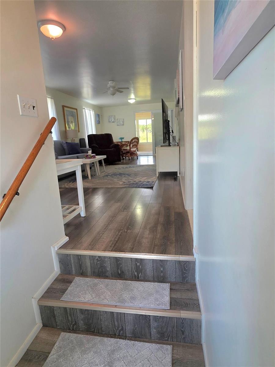 A view from a staircase looking into a living room with wood-look flooring — 12310 SE 143rd Avenue, FL 34974, FL