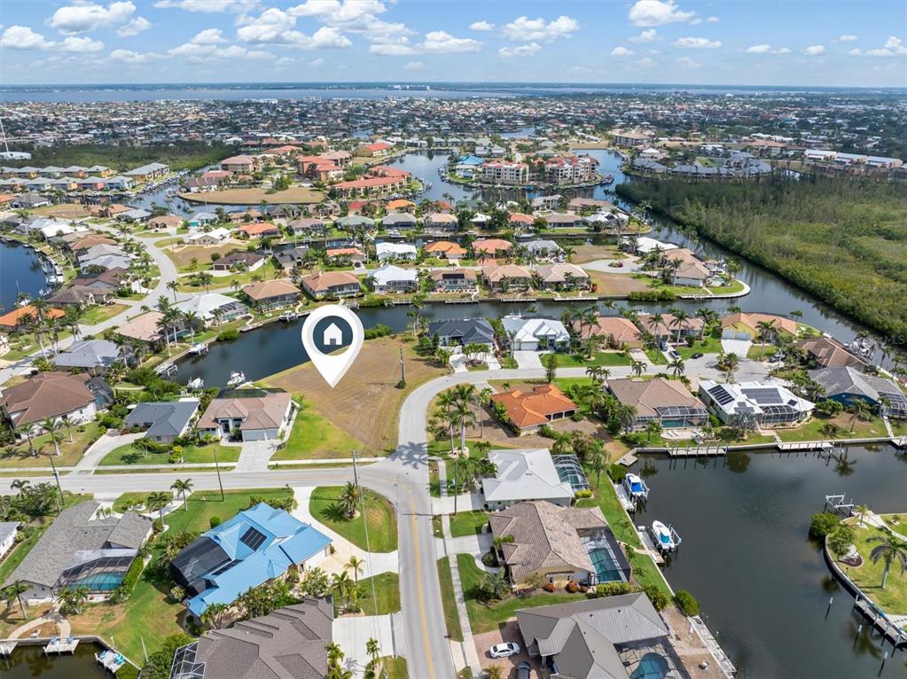 An aerial view shows a vacant waterfront lot marked by a house icon in a neighborhood — 1466 KIWI COURT, PUNTA GORDA, FL