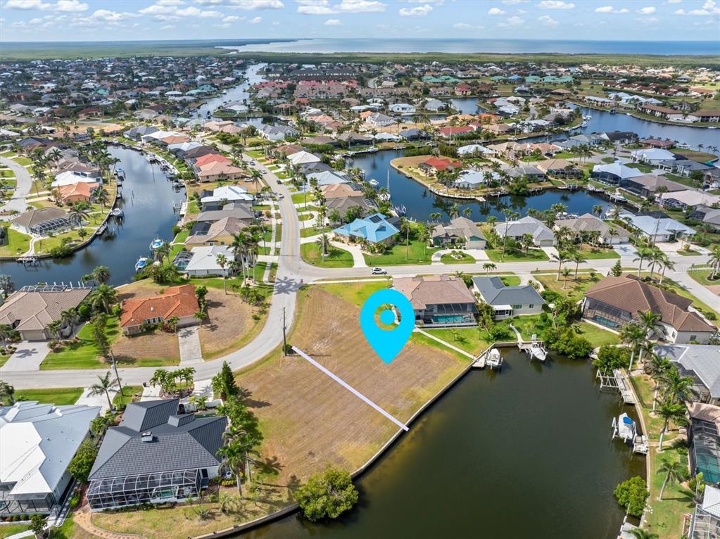 An aerial view shows a vacant waterfront lot marked with a blue location pin — 1466 KIWI COURT, PUNTA GORDA, FL