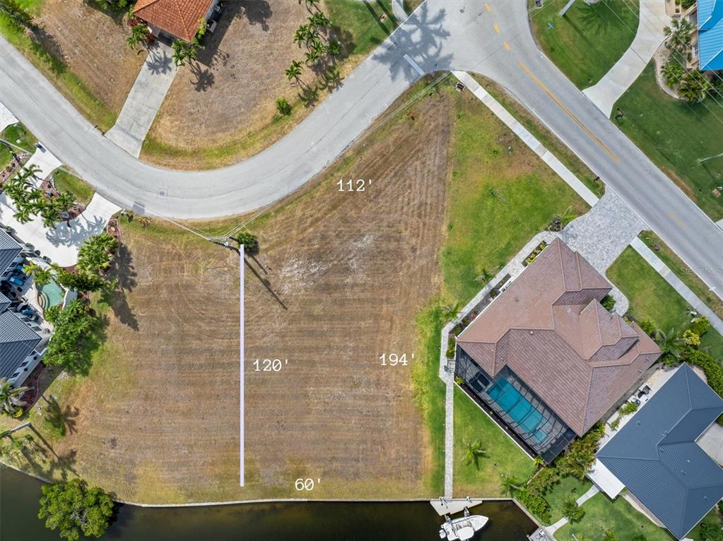 This aerial view shows a vacant, trapezoidal waterfront lot with labeled property dimensions — 1466 KIWI COURT, PUNTA GORDA, FL