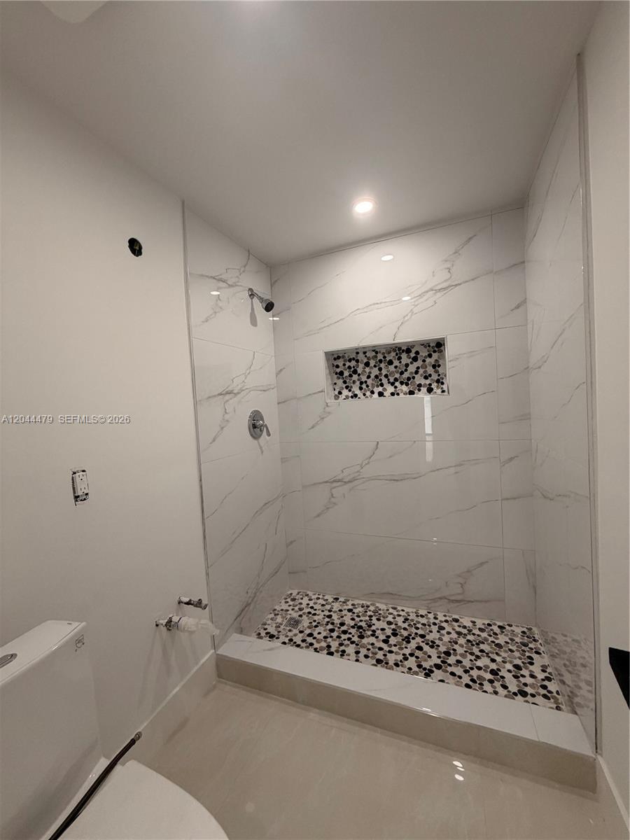 A bathroom features a walk-in shower with white marble-look tiles and a pebble-stone floor — 191 SE 6th Ave, Hialeah FL 33010, HIALEAH, FL