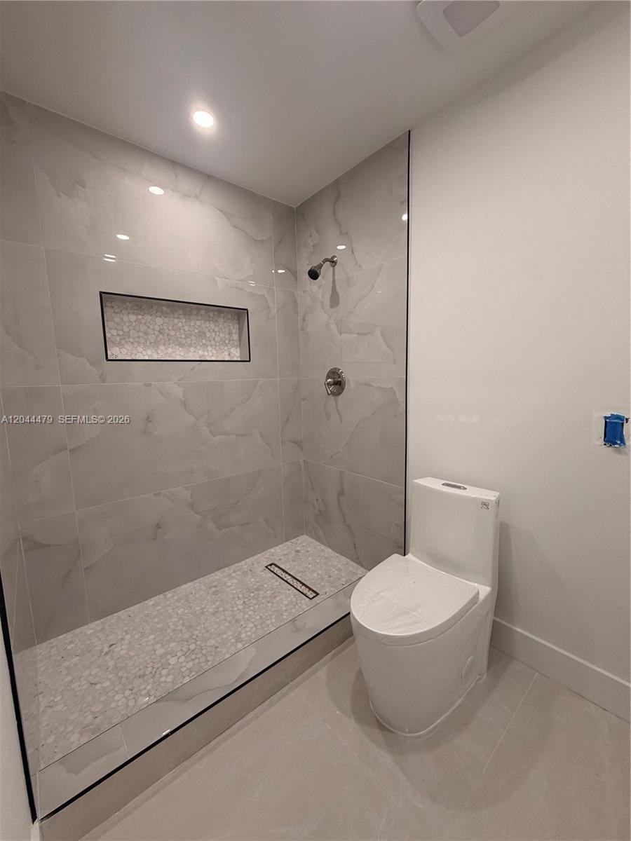 A modern bathroom features a walk-in shower with gray tile and a white toilet — 191 SE 6th Ave, Hialeah FL 33010, HIALEAH, FL