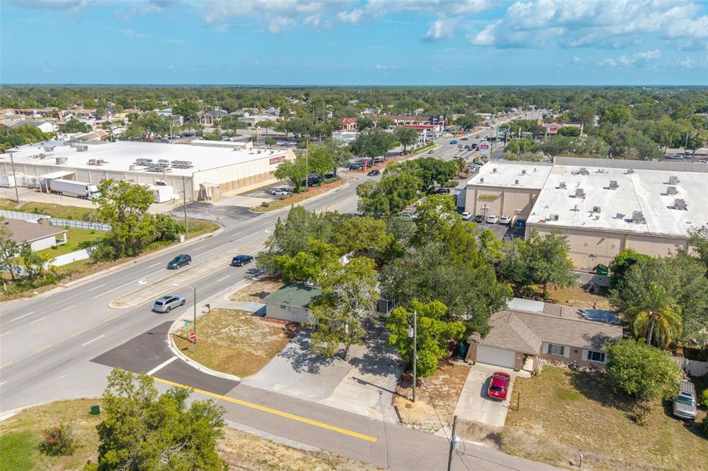 An aerial view shows a residential property situated next to a commercial shopping center — 1492 MARINER BOULEVARD, SPRING HILL, FL