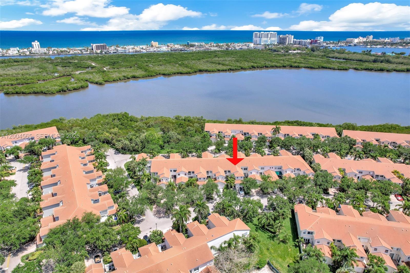 An aerial view shows a residential complex with terracotta roofs surrounded by trees and water — 1675 Yellowheart Way, Hollywood FL 33019, HOLLYWOOD, FL