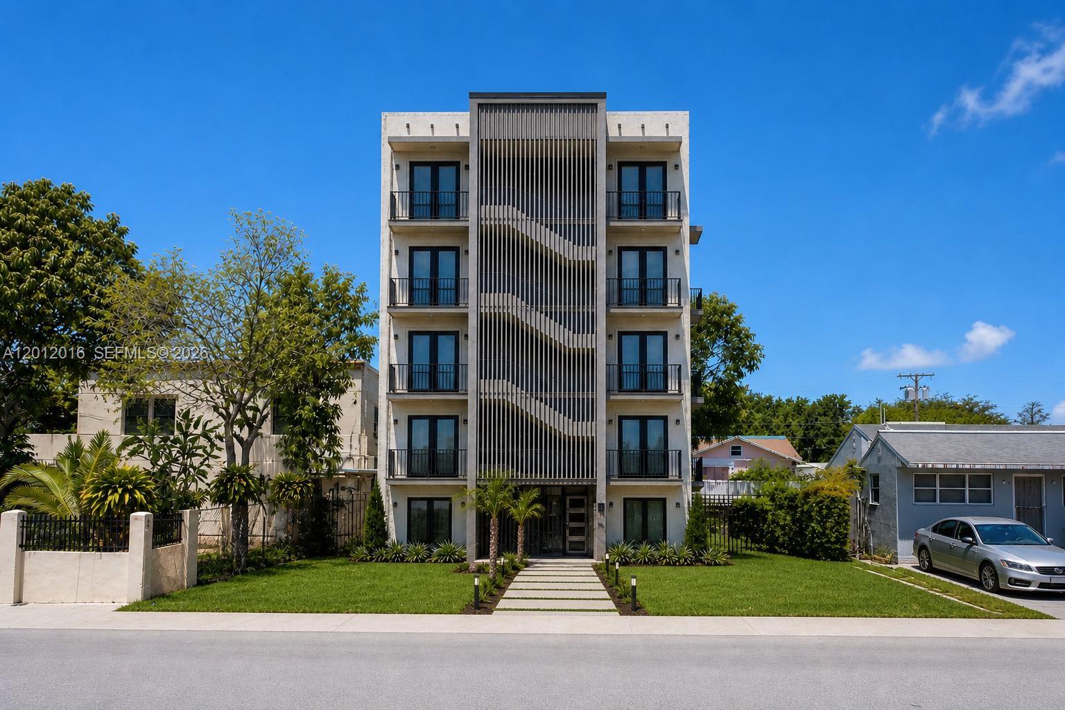 A modern five-story apartment building with a central staircase and balconies under a blue sky — 285 NE 55th St, Miami FL 33137, MIAMI, FL