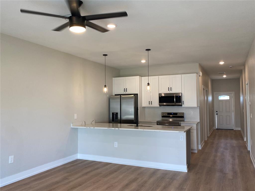 A kitchen with white cabinets, stainless steel appliances, and a breakfast bar island — 10524 PENDLETON AVENUE, ENGLEWOOD, FL