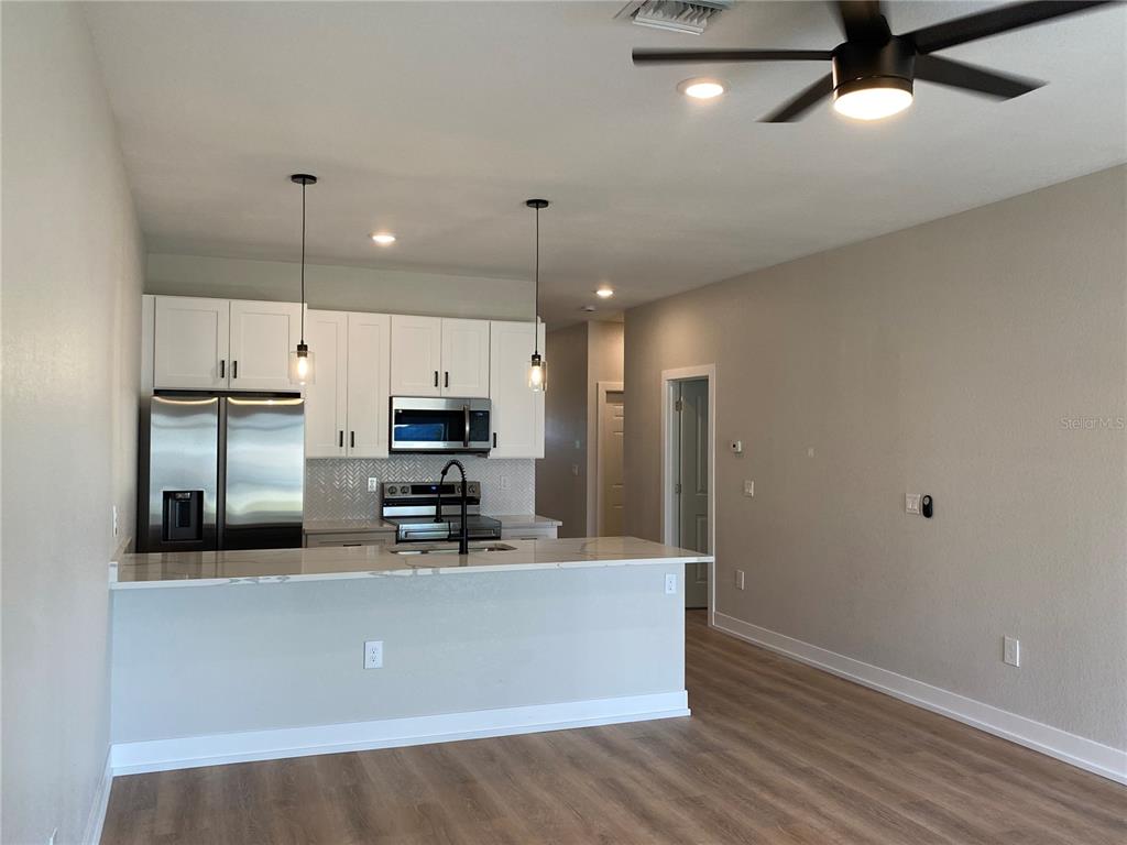 A kitchen with white cabinets, stainless steel appliances, and a breakfast bar island — 10524 PENDLETON AVENUE, ENGLEWOOD, FL