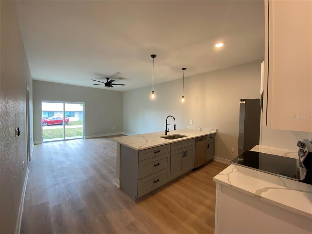A kitchen with gray cabinets and a white marble-look island overlooks an open living area — 10524 PENDLETON AVENUE, ENGLEWOOD, FL