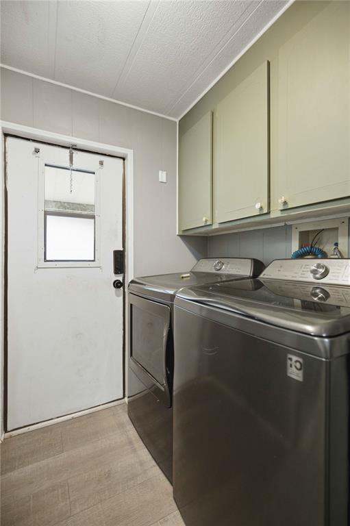 A laundry room features grey walls, light wood-look flooring, green cabinets, and a side-by-side washer-dryer — 12313 SE 86TH AVENUE, BELLEVIEW, FL