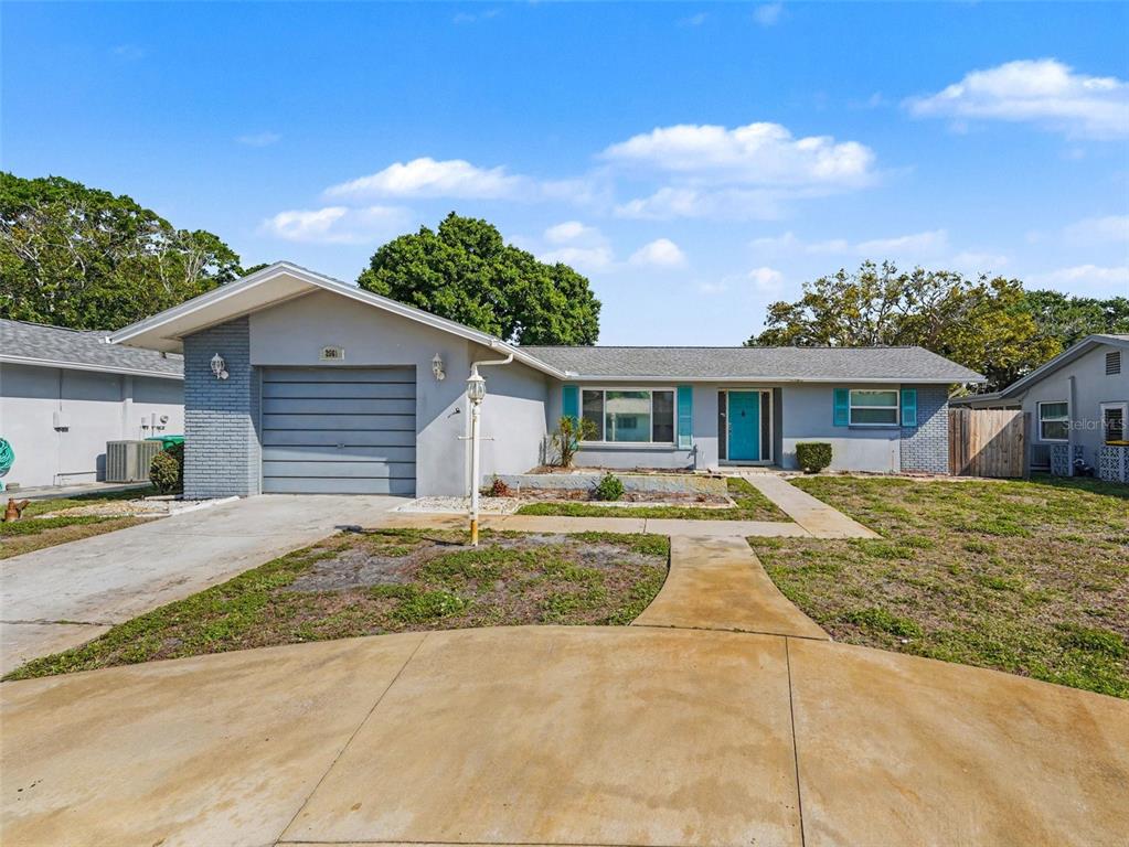 A single-story house with a gray brick facade, a garage, and a teal front door — 2561 BLACKWOOD CIRCLE, CLEARWATER, FL