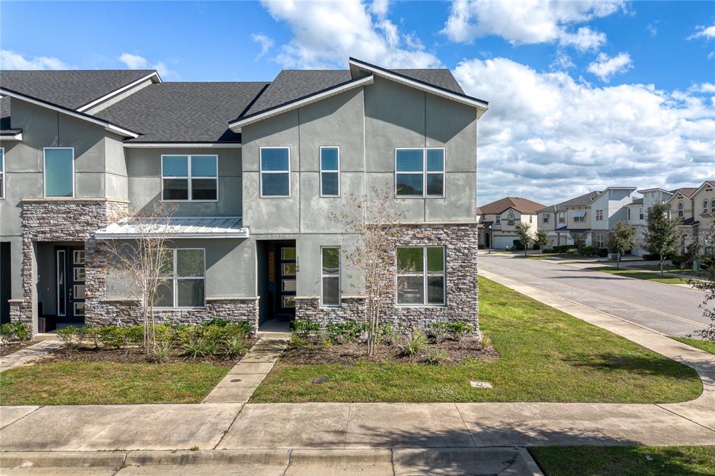 A two-story townhouse with a stone and stucco exterior sits next to a suburban street — 1700 TROPICAL PALMS CIRCLE, KISSIMMEE, FL