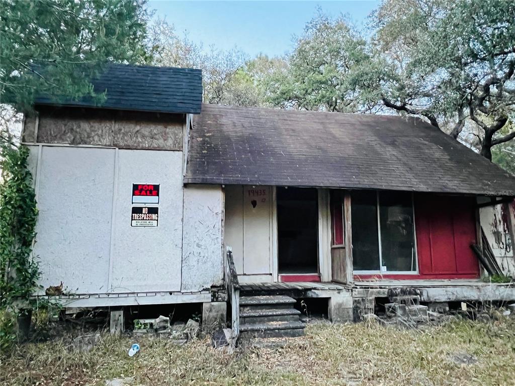 A dilapidated, single-story house with a weathered roof, boarded-up walls, and a front porch — 19435 SE 92ND PLACE, OCKLAWAHA, FL