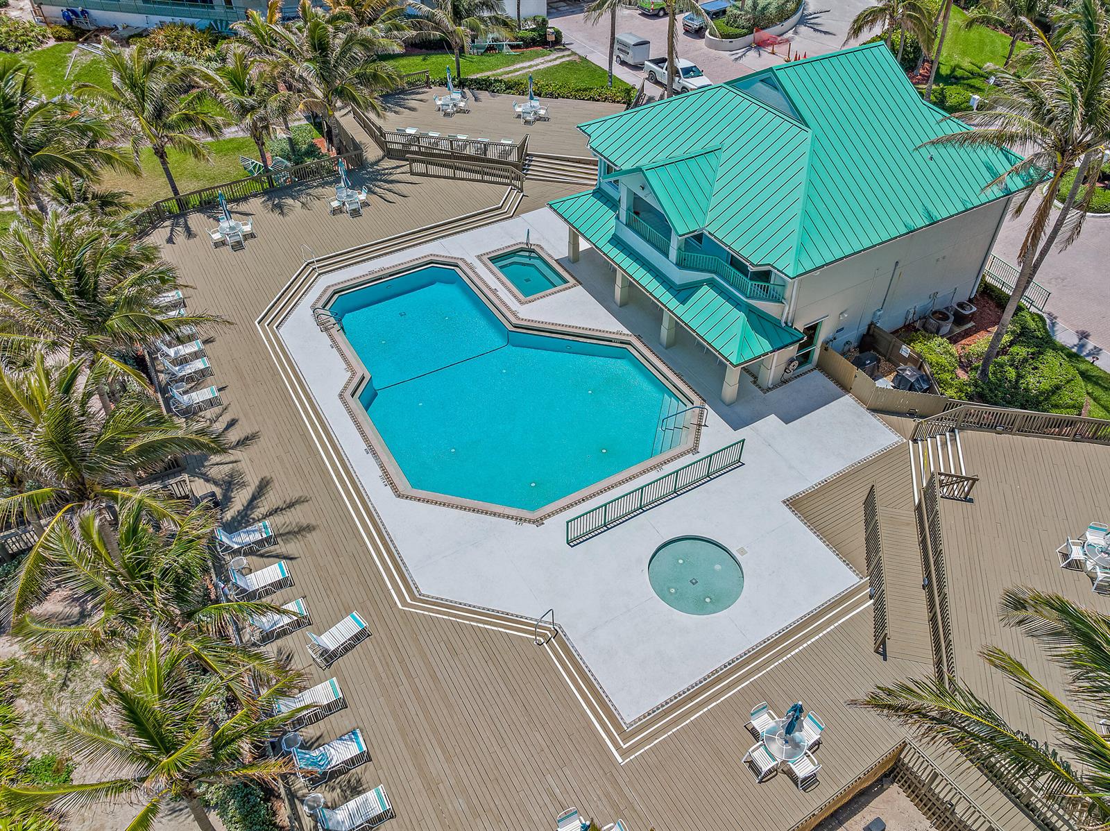 An aerial view shows a swimming pool, hot tub, and clubhouse with a green roof — 8650 S Ocean Drive # 306, Jensen Beach FL 34957, JENSEN BEACH, FL