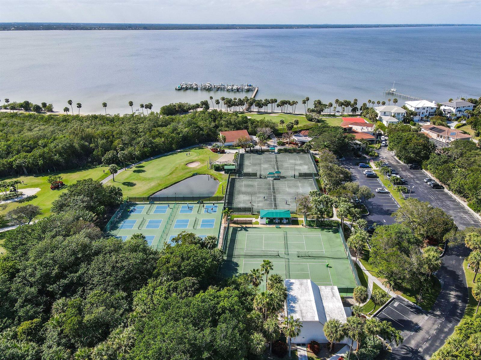 Aerial view of a tennis complex featuring multiple courts, a pond, and surrounding lush greenery — 8650 S Ocean Drive # 306, Jensen Beach FL 34957, JENSEN BEACH, FL