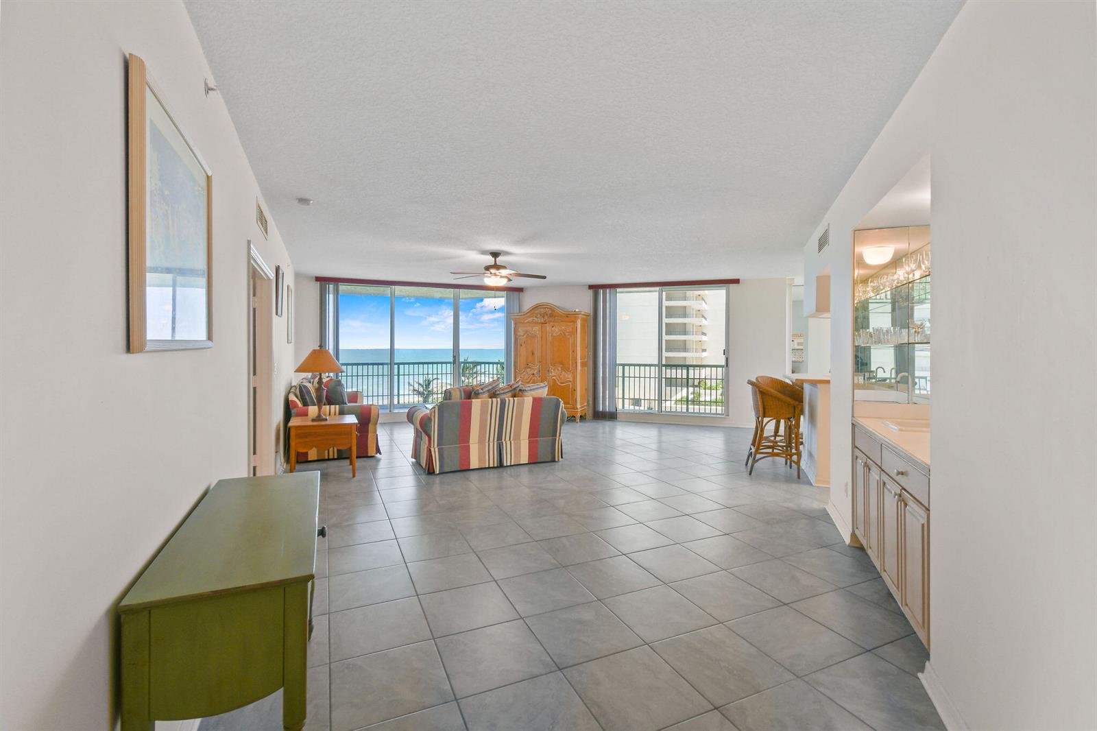 A spacious living room with tile floors, a wet bar, and a balcony overlooking the ocean — 8650 S Ocean Drive # 306, Jensen Beach FL 34957, JENSEN BEACH, FL