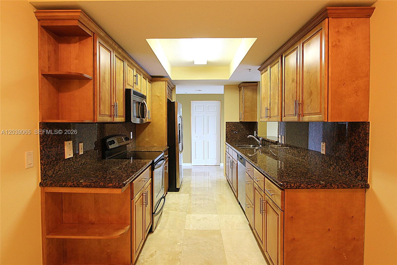 A galley kitchen features wood cabinets, granite countertops, and stainless steel appliances — 3530 SW 22nd St # 505, Miami FL 33145, MIAMI, FL