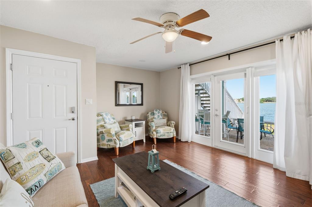 A living room features wood floors, a ceiling fan, two patterned chairs, and glass doors — 5117 SALMON DRIVE SE UNIT B, ST PETERSBURG, FL