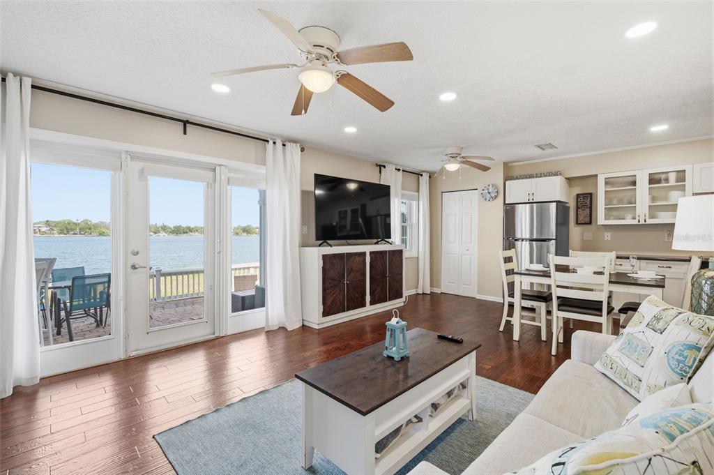 A living room with wood floors, a ceiling fan, and sliding doors overlooking the water — 5117 SALMON DRIVE SE UNIT B, ST PETERSBURG, FL