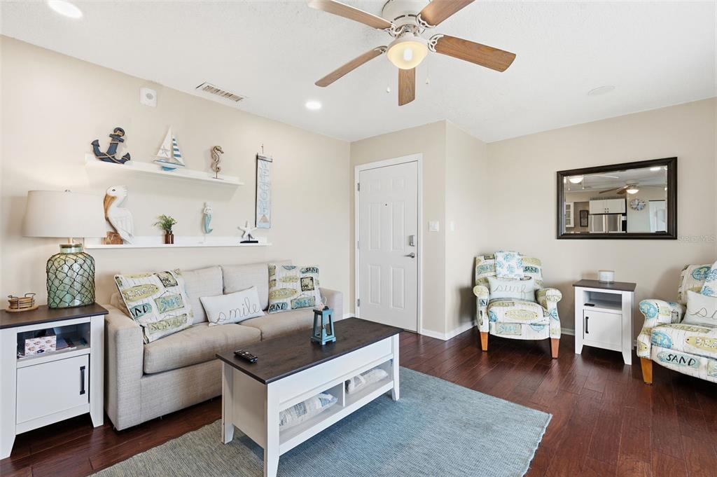 A living room features a beige sofa, two patterned armchairs, and coastal-themed wall decor — 5117 SALMON DRIVE SE UNIT B, ST PETERSBURG, FL