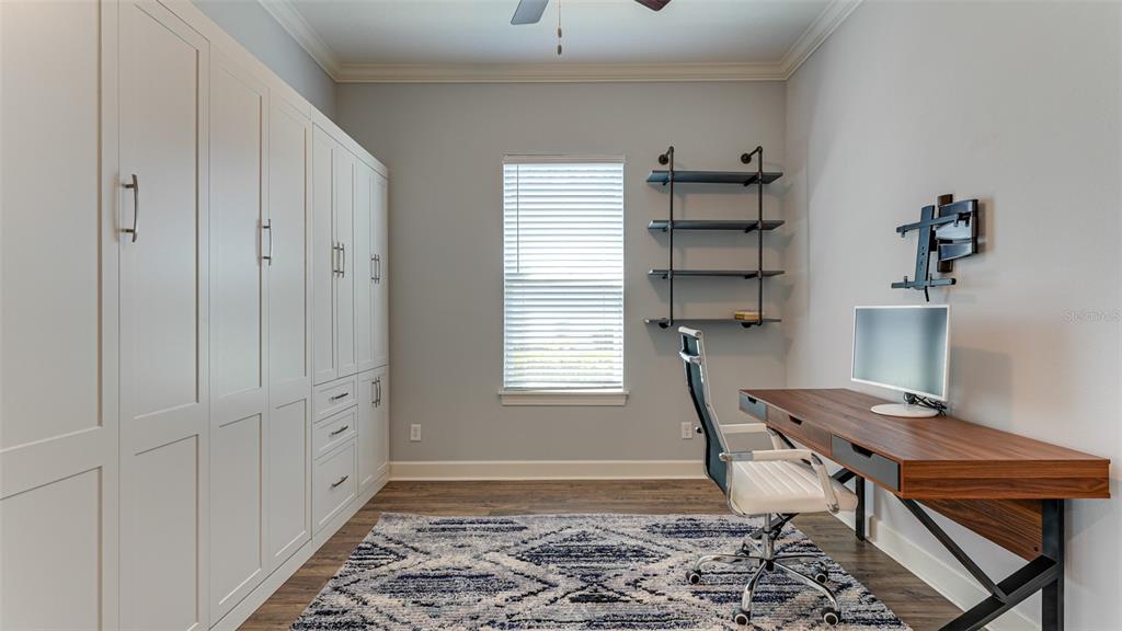 A home office features built-in white cabinetry, a wooden desk, an office chair, and shelving — 4511 TERRAZZA COURT, LAKEWOOD RANCH, FL