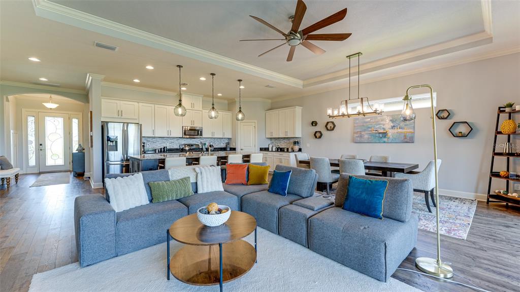An open-concept living area features a grey sectional sofa, dining space, and kitchen with white cabinetry — 4511 TERRAZZA COURT, LAKEWOOD RANCH, FL