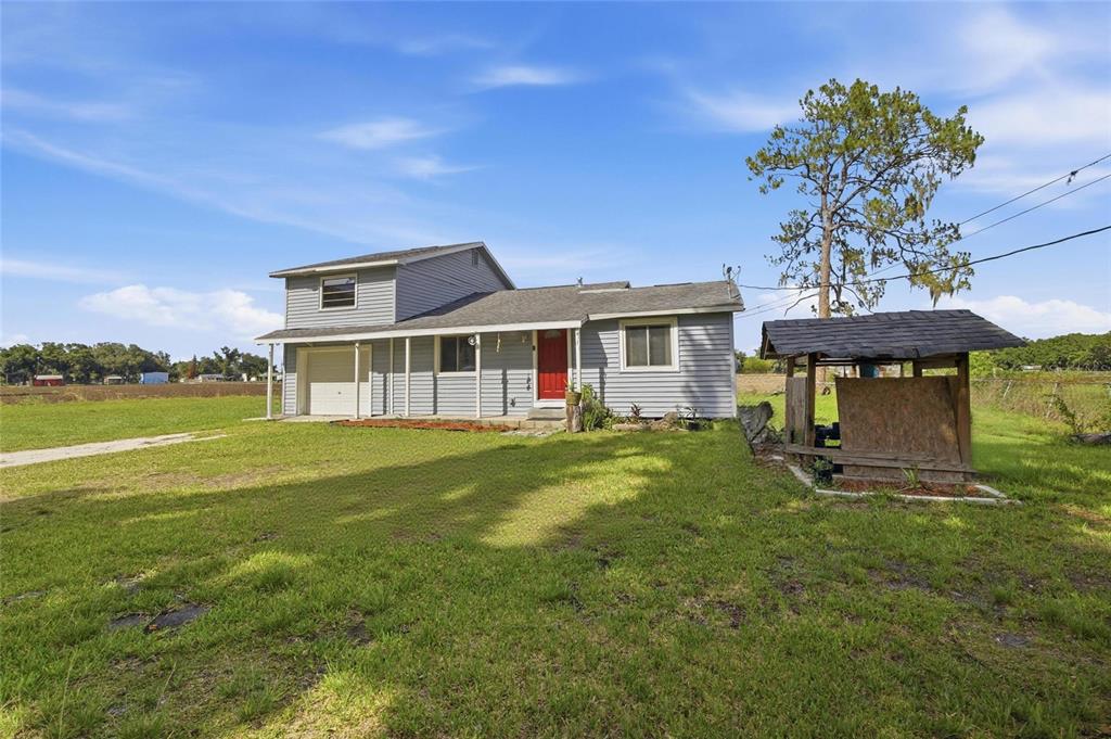 A two-story house with gray siding and a red front door sits on a lawn — 4710 CORONET ROAD, PLANT CITY, FL