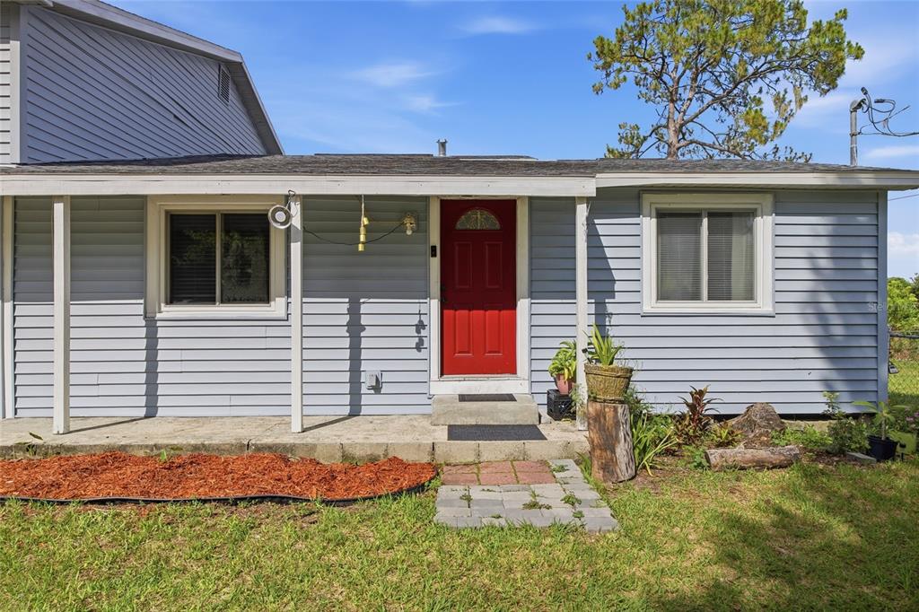 A light blue, single-story house exterior features a red front door and a covered porch — 4710 CORONET ROAD, PLANT CITY, FL