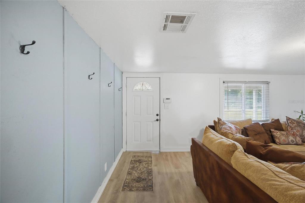 A living room features light blue paneled walls with coat hooks and a white door — 4710 CORONET ROAD, PLANT CITY, FL