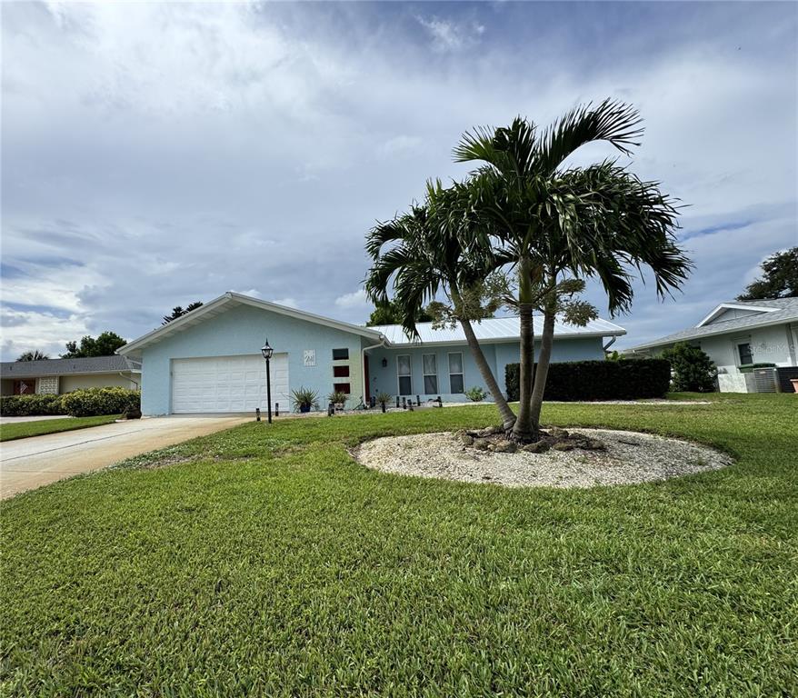 A light blue single-story house with a white garage door and a palm tree in front — 6813 13TH AVENUE DRIVE W, BRADENTON, FL