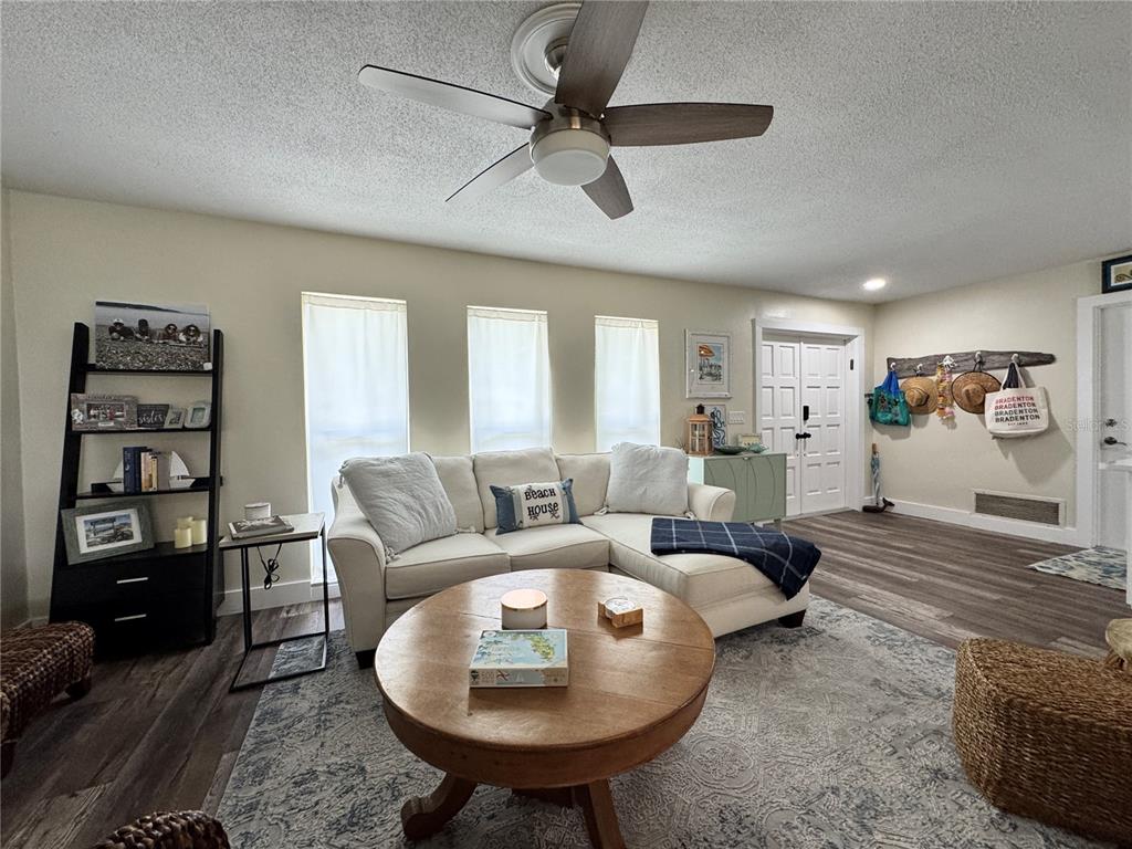 A living room features a sectional sofa, a round wooden coffee table, and a ceiling fan — 6813 13TH AVENUE DRIVE W, BRADENTON, FL