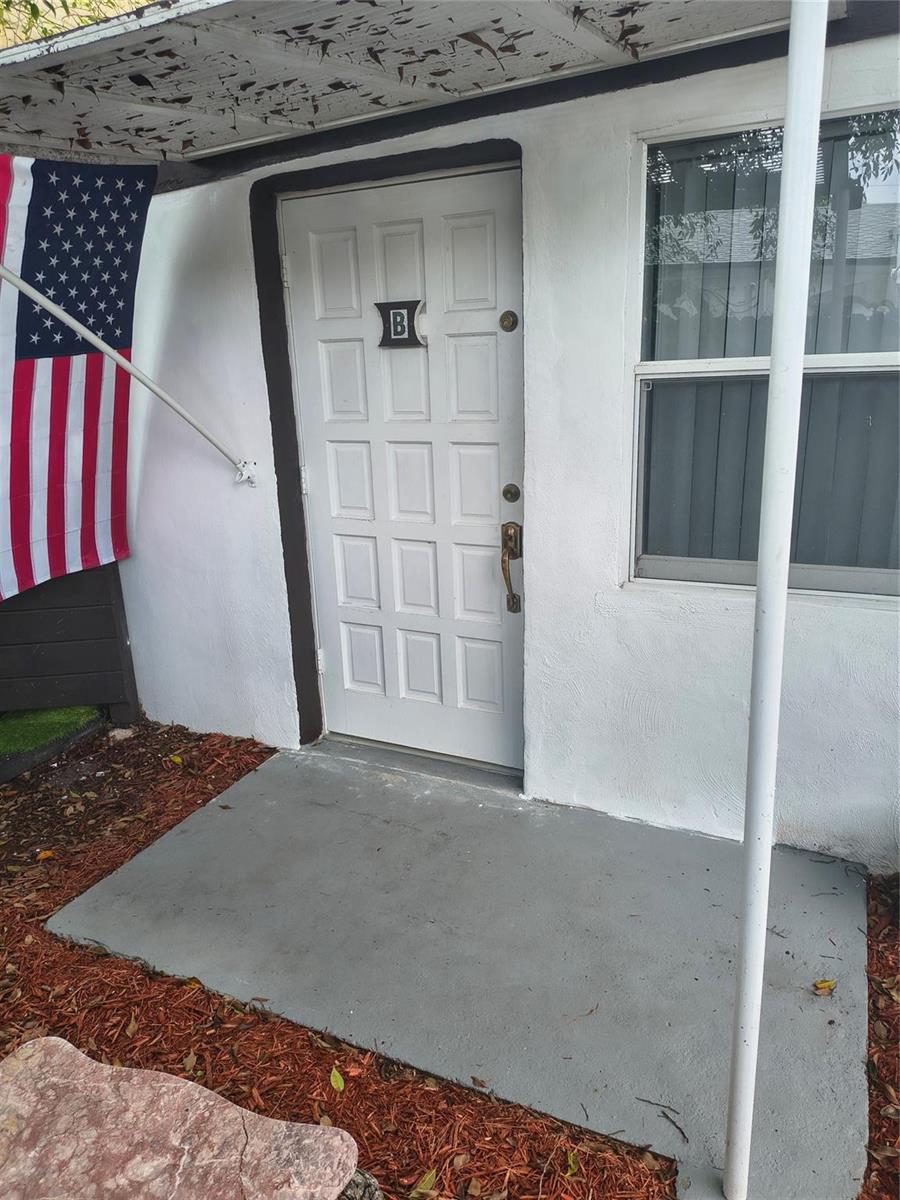 A white front door marked with a B sits beside an American flag and window — 2206 Coolidge Street Unit B, Hollywood FL 33020, HOLLYWOOD, FL