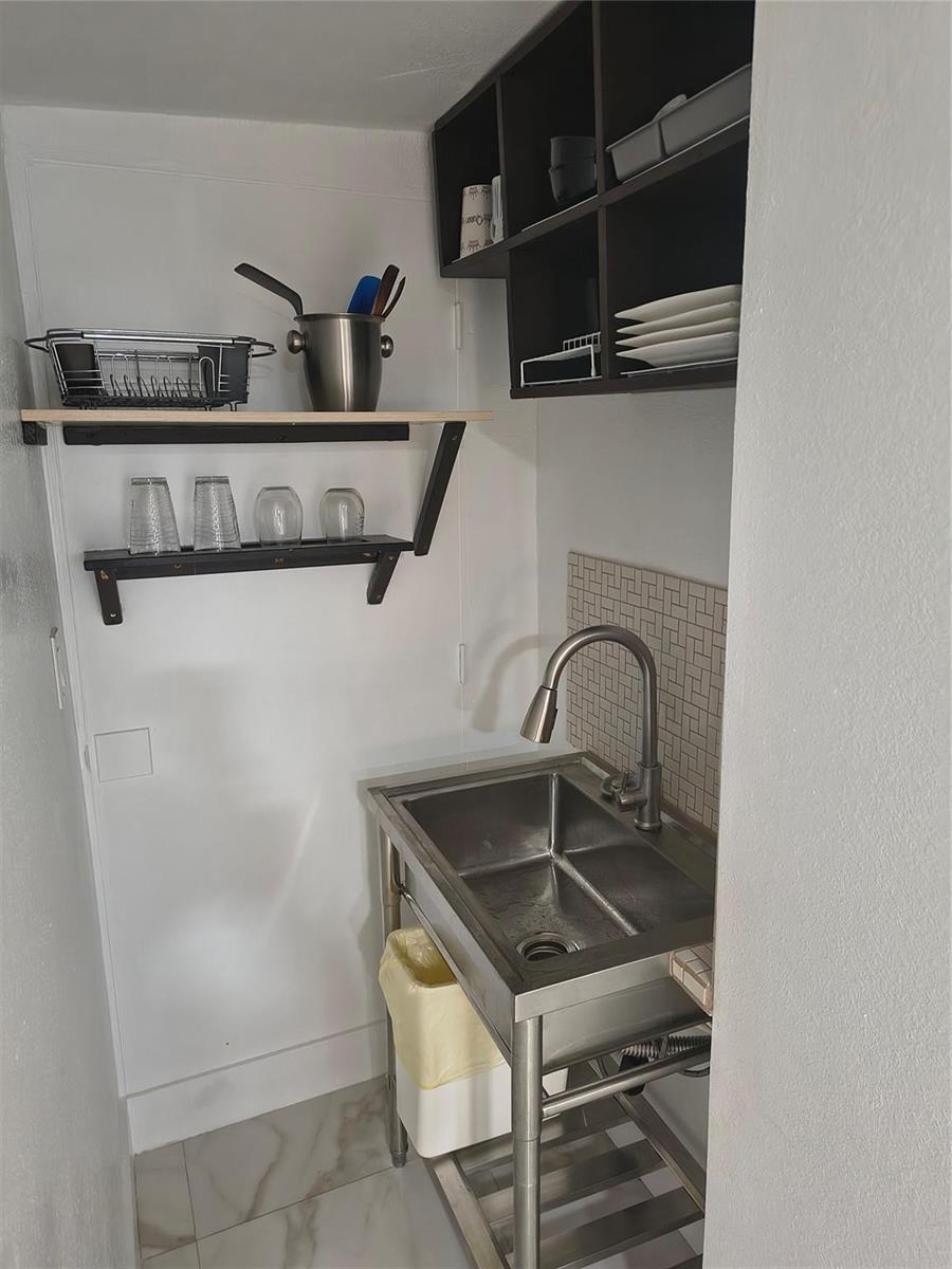 A small kitchen area features a stainless steel utility sink, open shelving, and dark cabinets — 2206 Coolidge Street Unit B, Hollywood FL 33020, HOLLYWOOD, FL