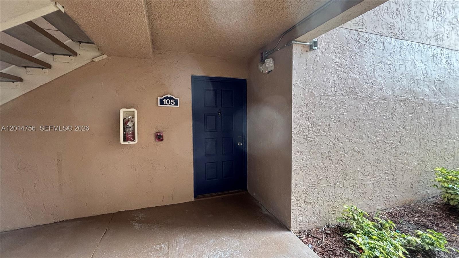 A dark blue front door labeled 105 is situated under an exterior staircase — 10420 SW 158th Ct # 105, Miami FL 33196, MIAMI, FL