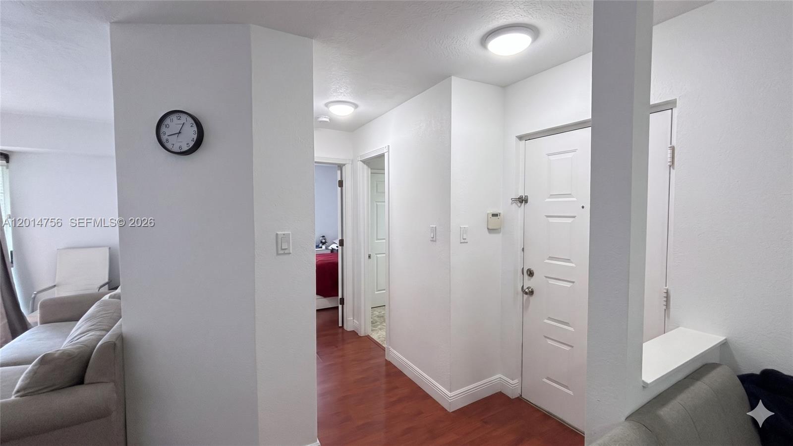 A white hallway with wood-look flooring leads to two doorways and a white entry door — 10420 SW 158th Ct # 105, Miami FL 33196, MIAMI, FL