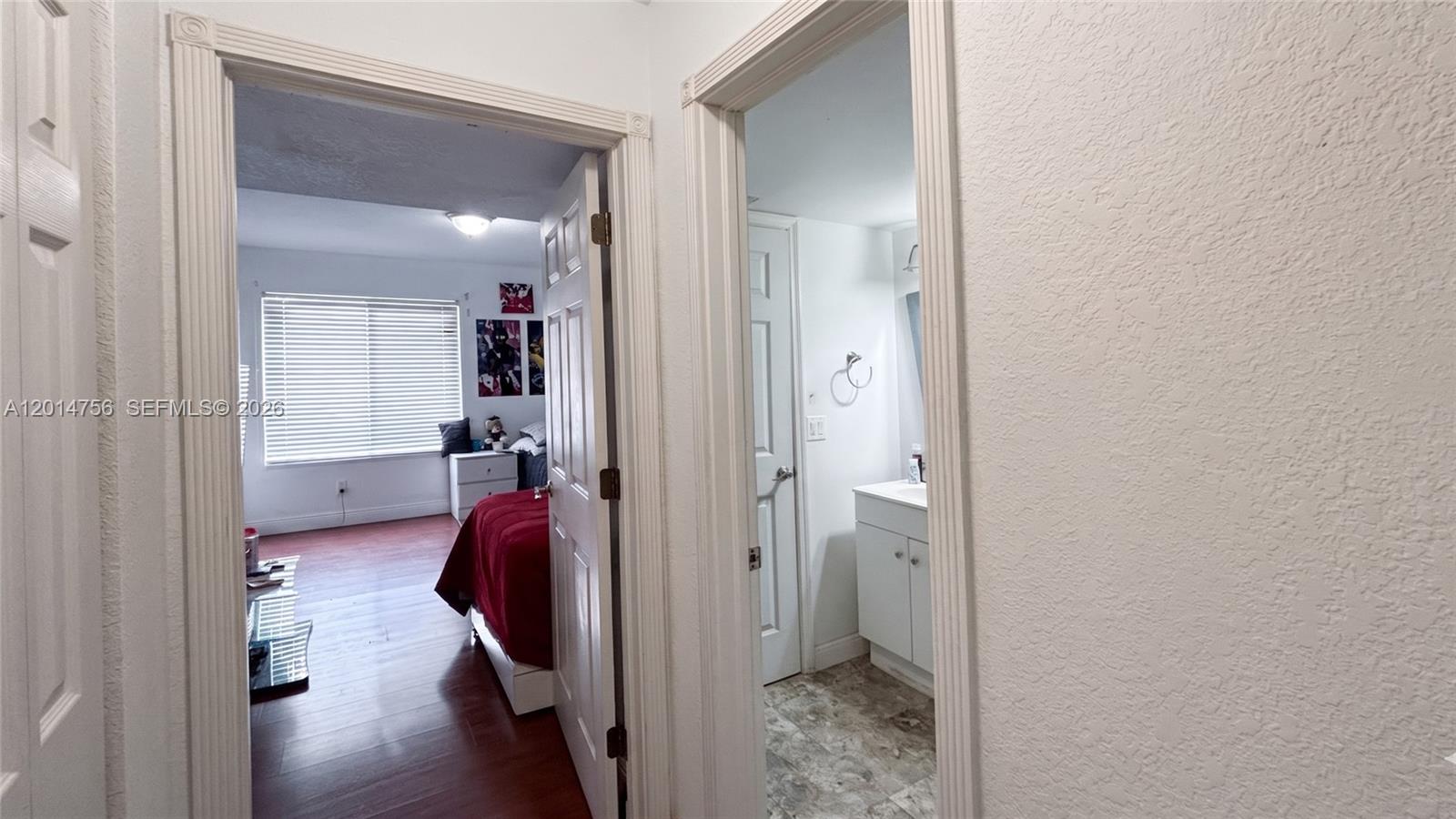 A hallway provides access to a bedroom with wood flooring and a tiled bathroom — 10420 SW 158th Ct # 105, Miami FL 33196, MIAMI, FL