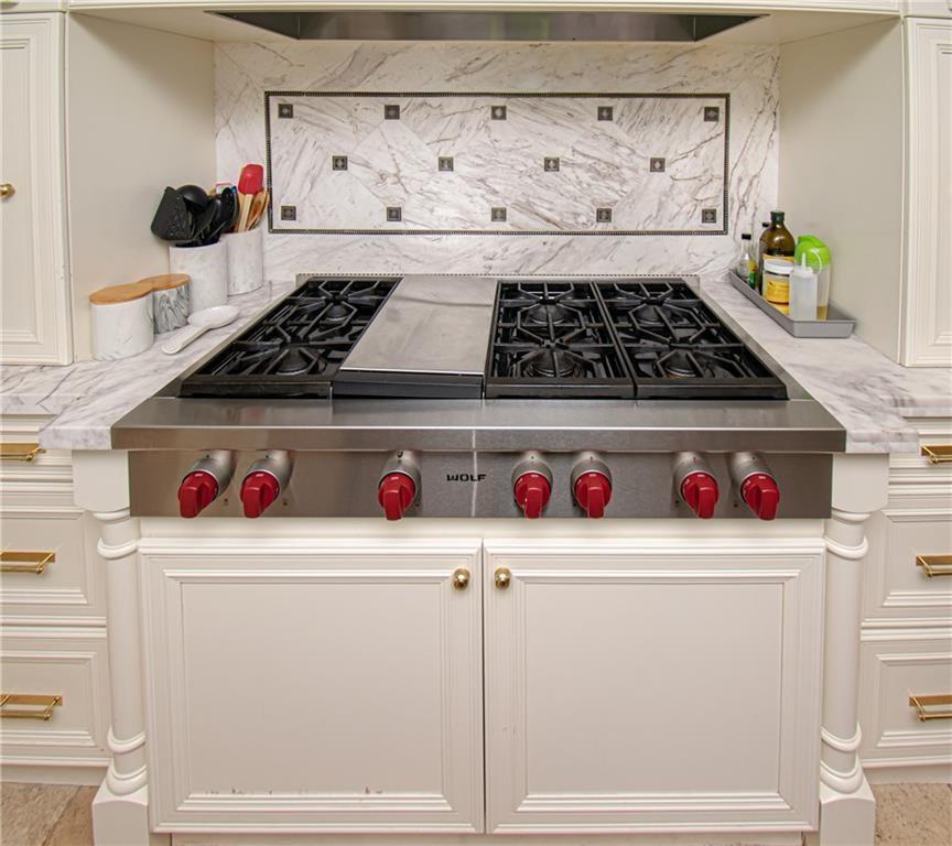 A stainless steel Wolf range with a griddle sits between white cabinets and marble countertops — 8208 Twin Lake Drive, Boca Raton FL 33496, BOCA RATON, FL