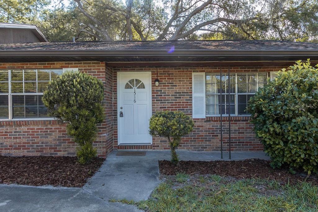 A brick exterior features a white front door, two windows, and small manicured shrubs — 1516 S BOUNDARY STREET, DELAND, FL
