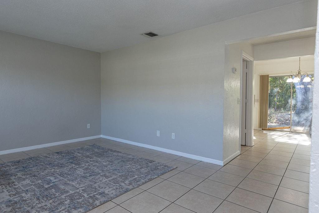 A living room with light gray walls, tile flooring, a patterned rug, and an adjacent dining area — 1516 S BOUNDARY STREET, DELAND, FL