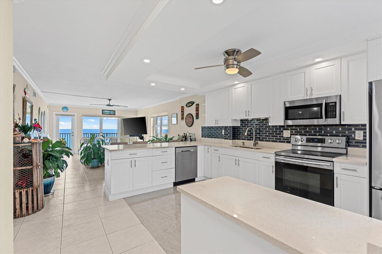A bright kitchen with white cabinets, quartz countertops, and a dark blue subway tile backsplash — 750 N Ocean Boulevard # 710, Pompano Beach FL 33062, POMPANO BEACH, FL
